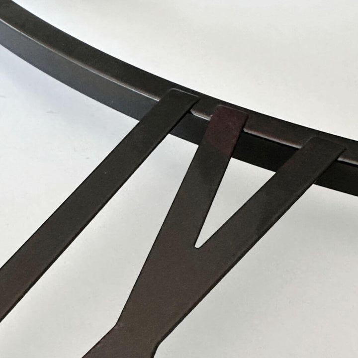 Close-up view of black Roman numerals with copper undertone on metal wall clock