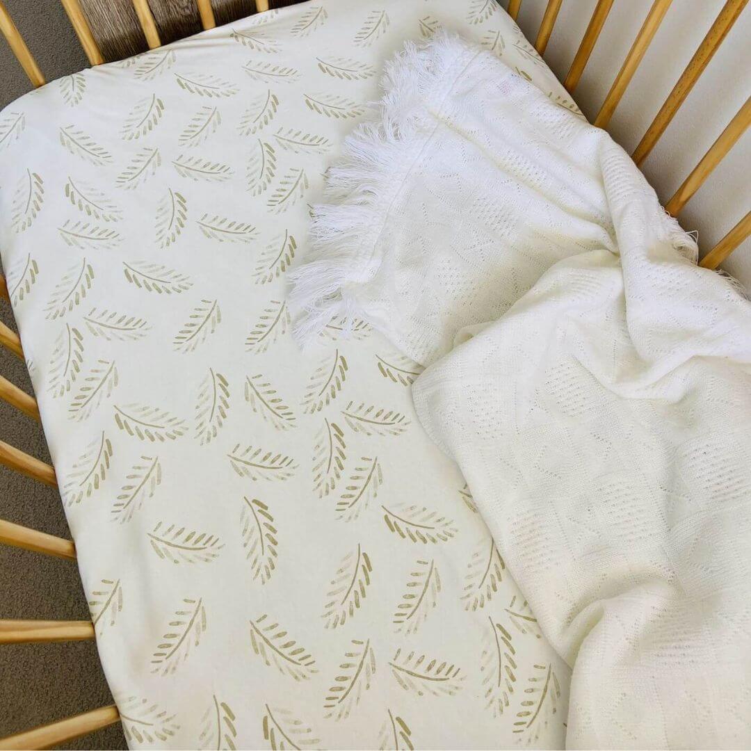 A soft, breathable Jersey Cotton Fitted Baby Cot Sheet in a natural Gold Fern pattern.