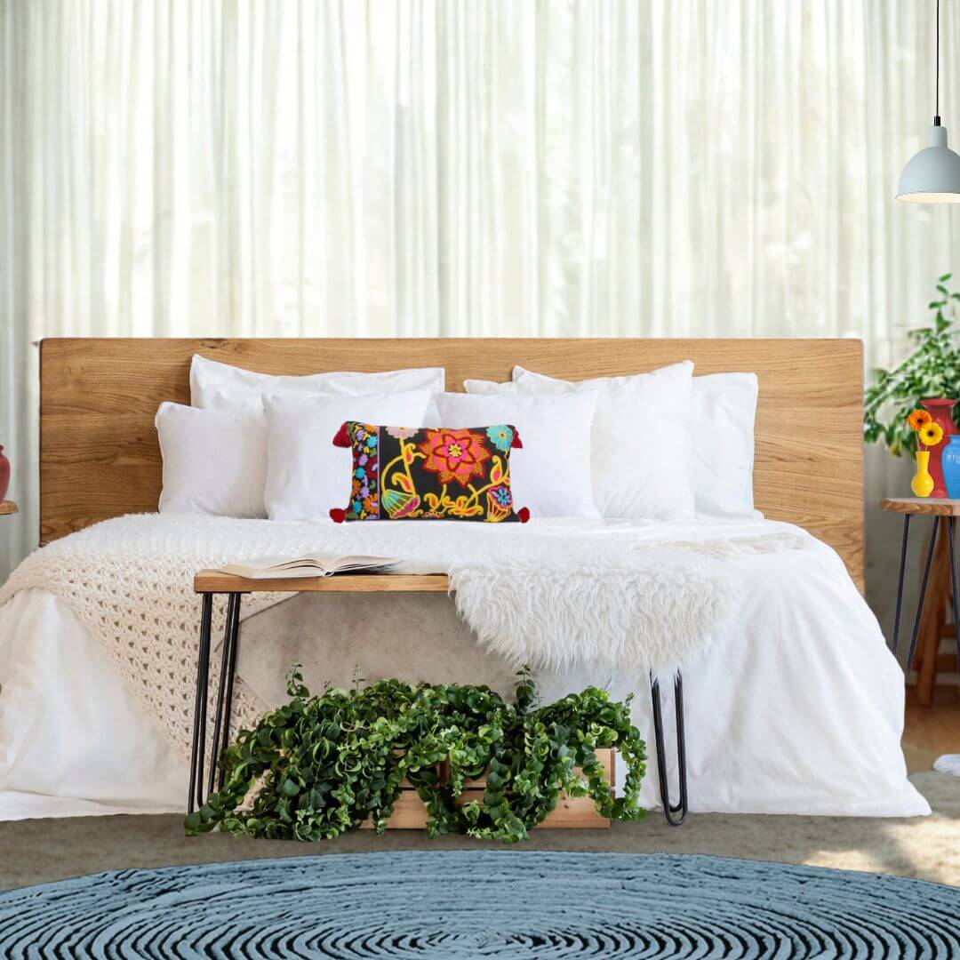 Bedroom with wooden headboard, white bedding, and colorful boho embroidered floral cushion