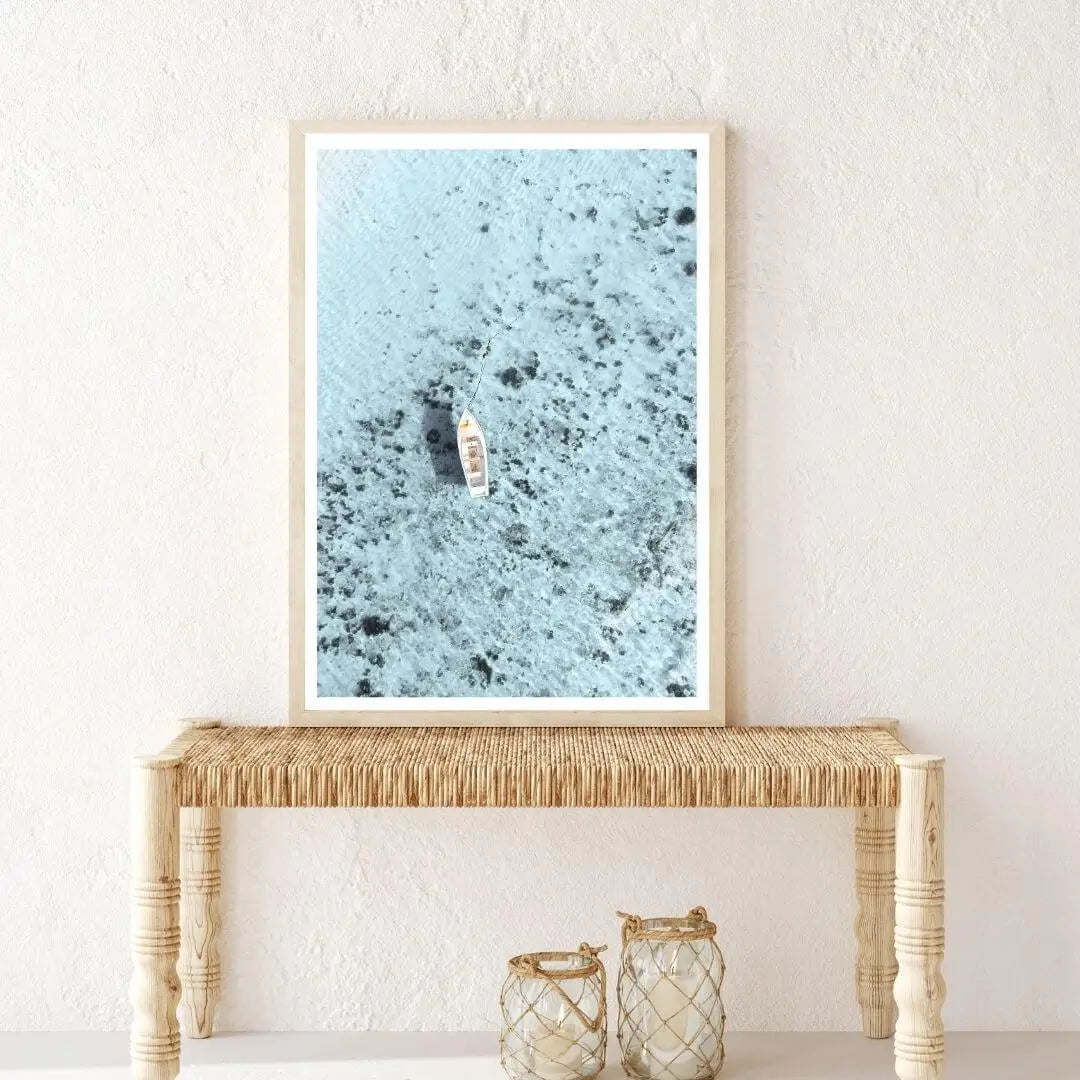 Coastal wall art print of a white boat on blue ocean in timber frame, styled in a hallway – Beautiful Home Decor.
