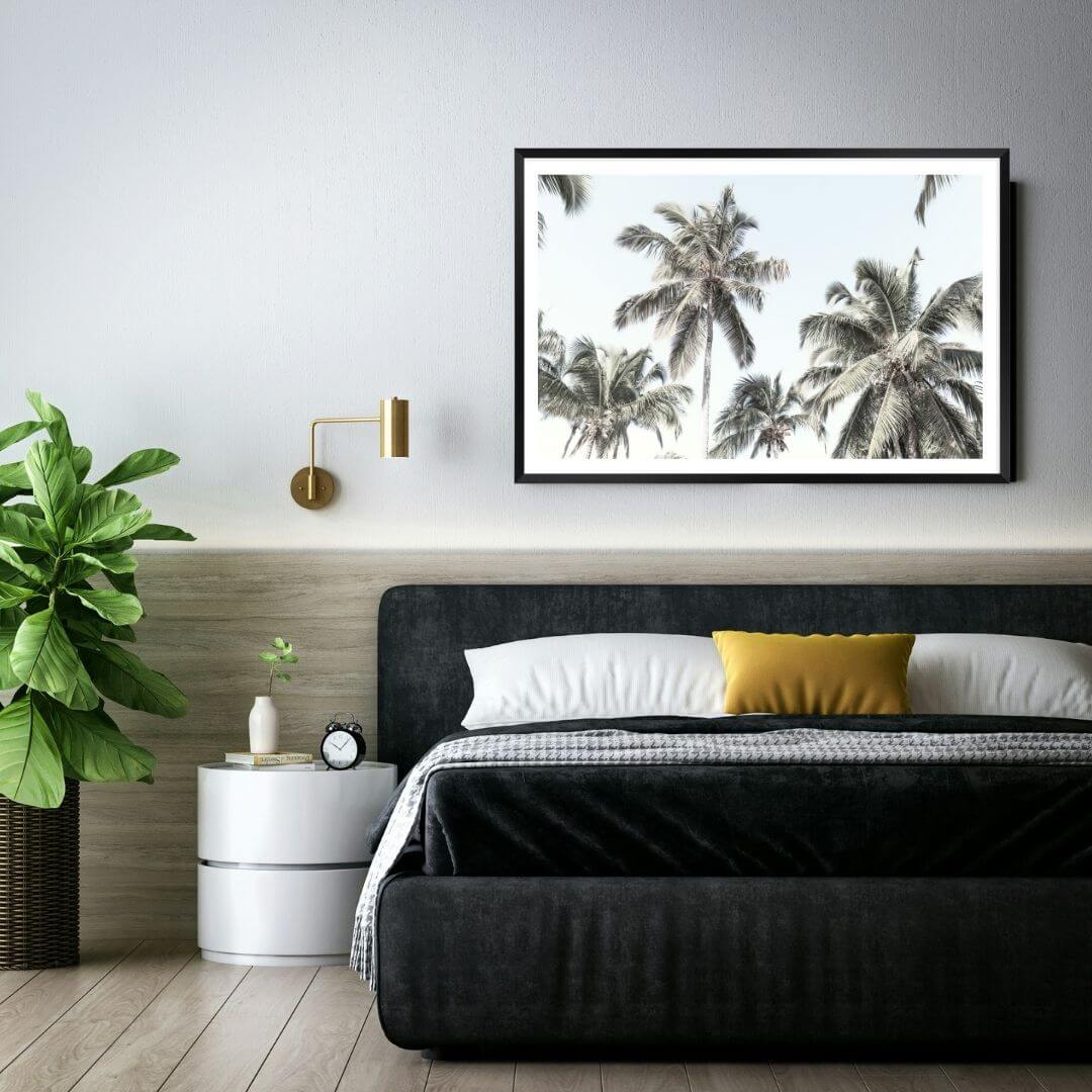 A wall art photo print of coastal palm trees and blue sky with a black frame for the wall in your bedroom