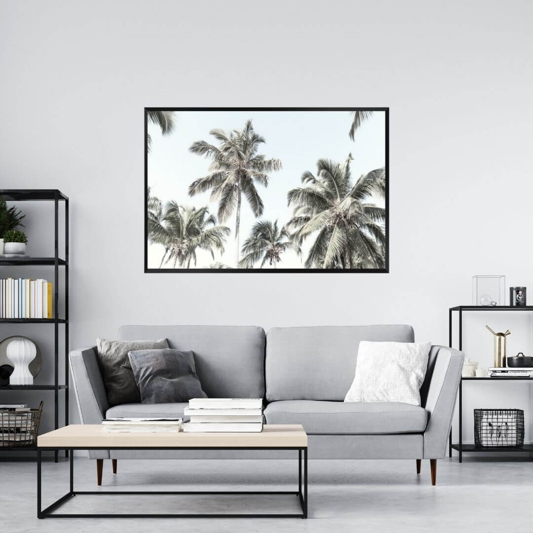 A wall art photo print of coastal palm trees and blue sky with a black frame or unframed to decorate a wall in your living room