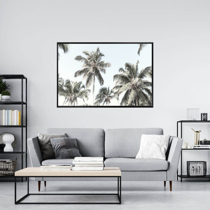 A wall art photo print of coastal palm trees and blue sky with a black frame or unframed to decorate a wall in your living room
