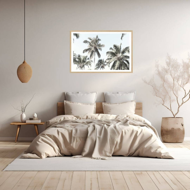 A wall art photo print of coastal palm trees and blue sky with a timber frame to style a coastal Australian bedroom walls