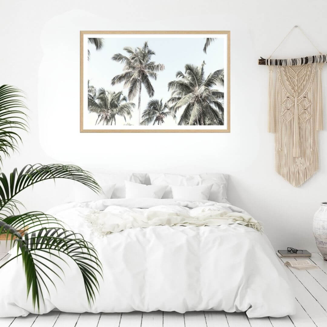 A wall art photo print of coastal palm trees and blue sky with a timber frame to style a coastal Australian bedroom