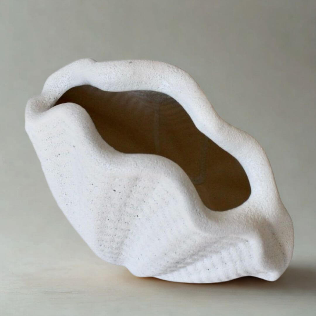 White ceramic oyster vase with textured surface on a light gray background