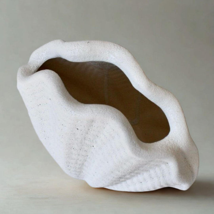 White ceramic oyster vase with textured surface on a light gray background