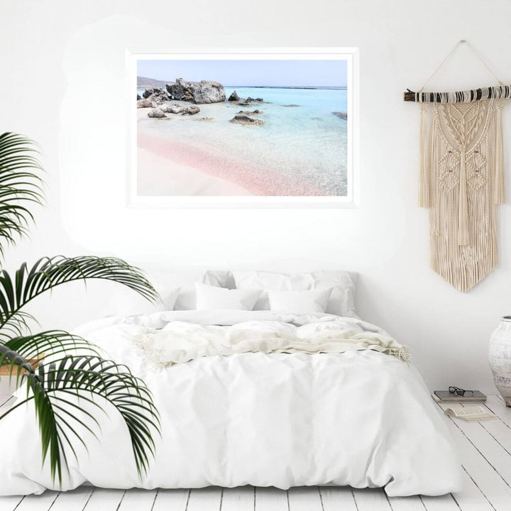 A coastal wall art photo print of a pink beach in Greece with a white frame to decorate your bedroom walls