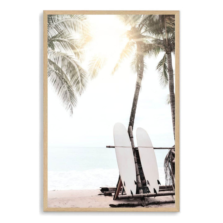 A photo wall art print of two white surf boards under the palm trees on a surfer beach in Hawaii in a timber frame.