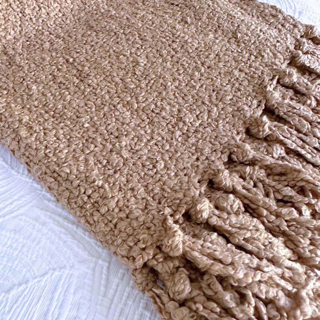 A gorgeous soft Jade throw in warm taupe with a boucle pattern and tassels, measuring 130cm x 160cm, to style your bedroom bed or living room sofa.