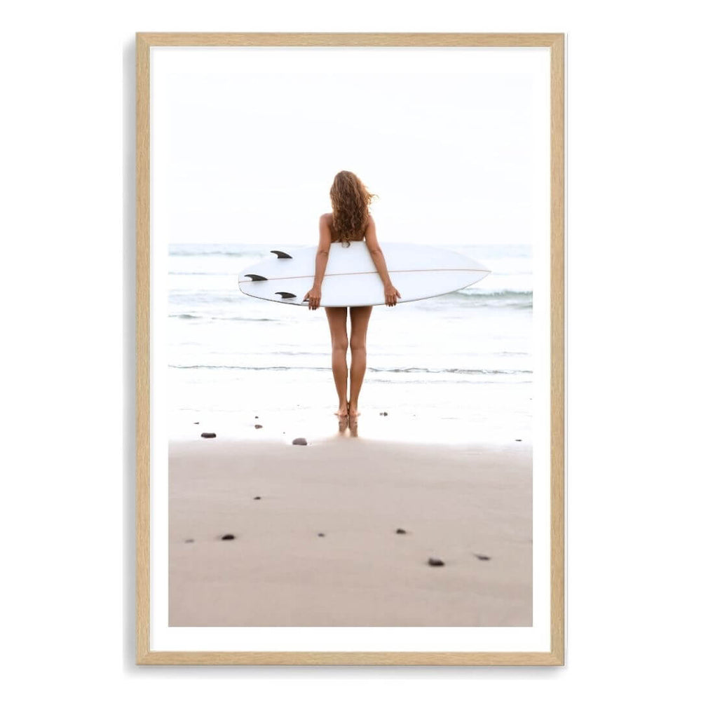 A wall art photo print of the girl with the surfboard with a timber frame, white border by Beautiful Home Decor