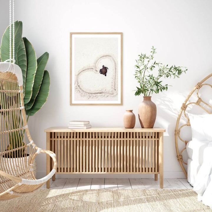 A coastal wall art photo print of a turtle in a heart on the beach with a timber frame or unframed for your coastal living room behind sofa