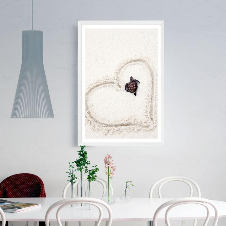 A wall art photo print of a turtle on the beach with a white frame, white border on dining room wall