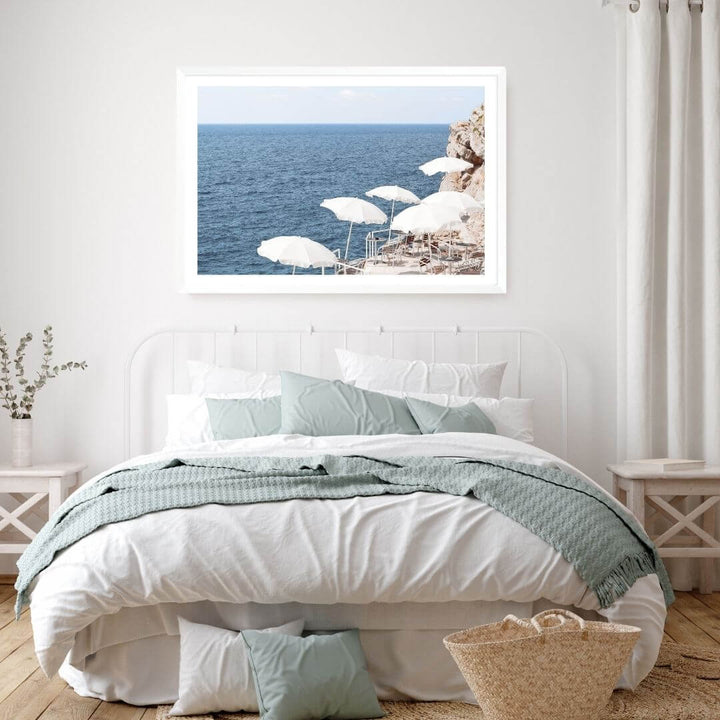 A wall art photo print of white umbrellas on an Amalffi Coast Beach Italy with a white frame or unframed for the wall above your bedroom bed