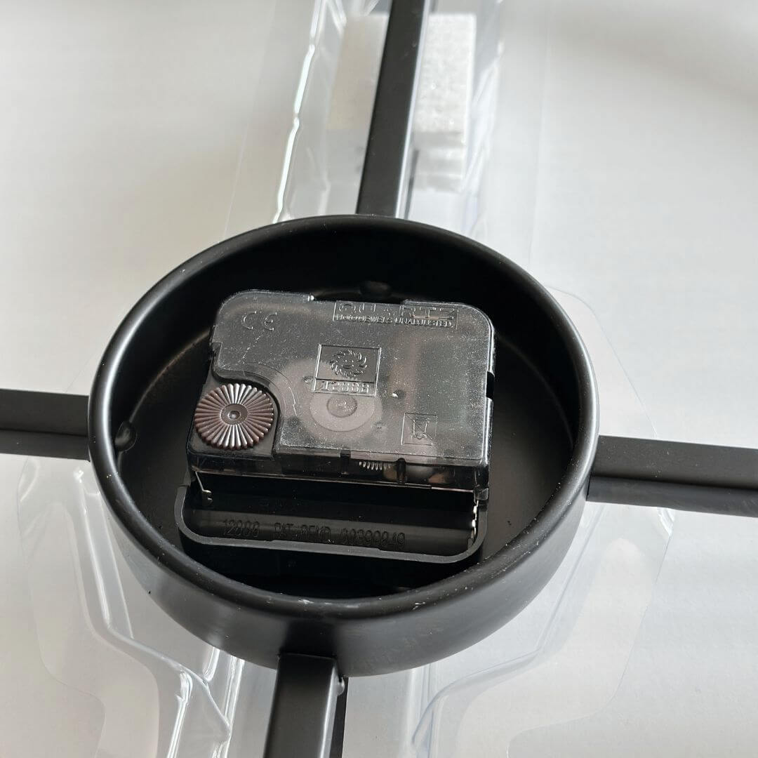 Close-up of battery holder on black metal wall clock.