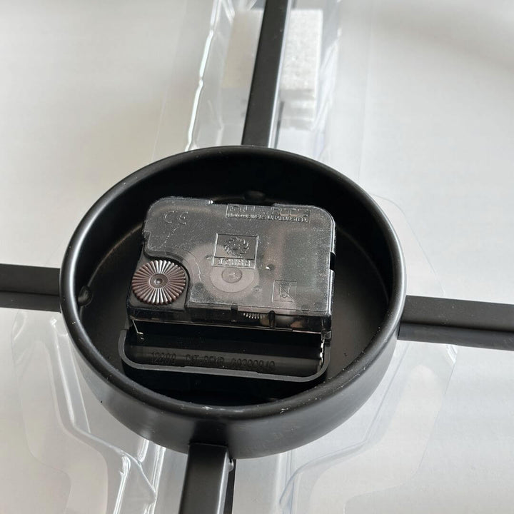 Close-up of battery holder on black metal wall clock.