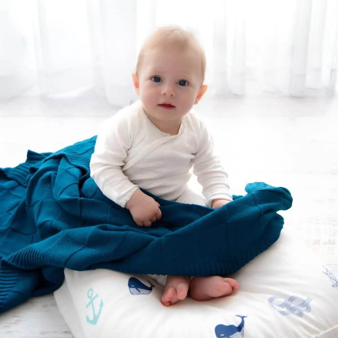A soft dark blue, sea glass green knitted Baby Blanket to wrap baby in.