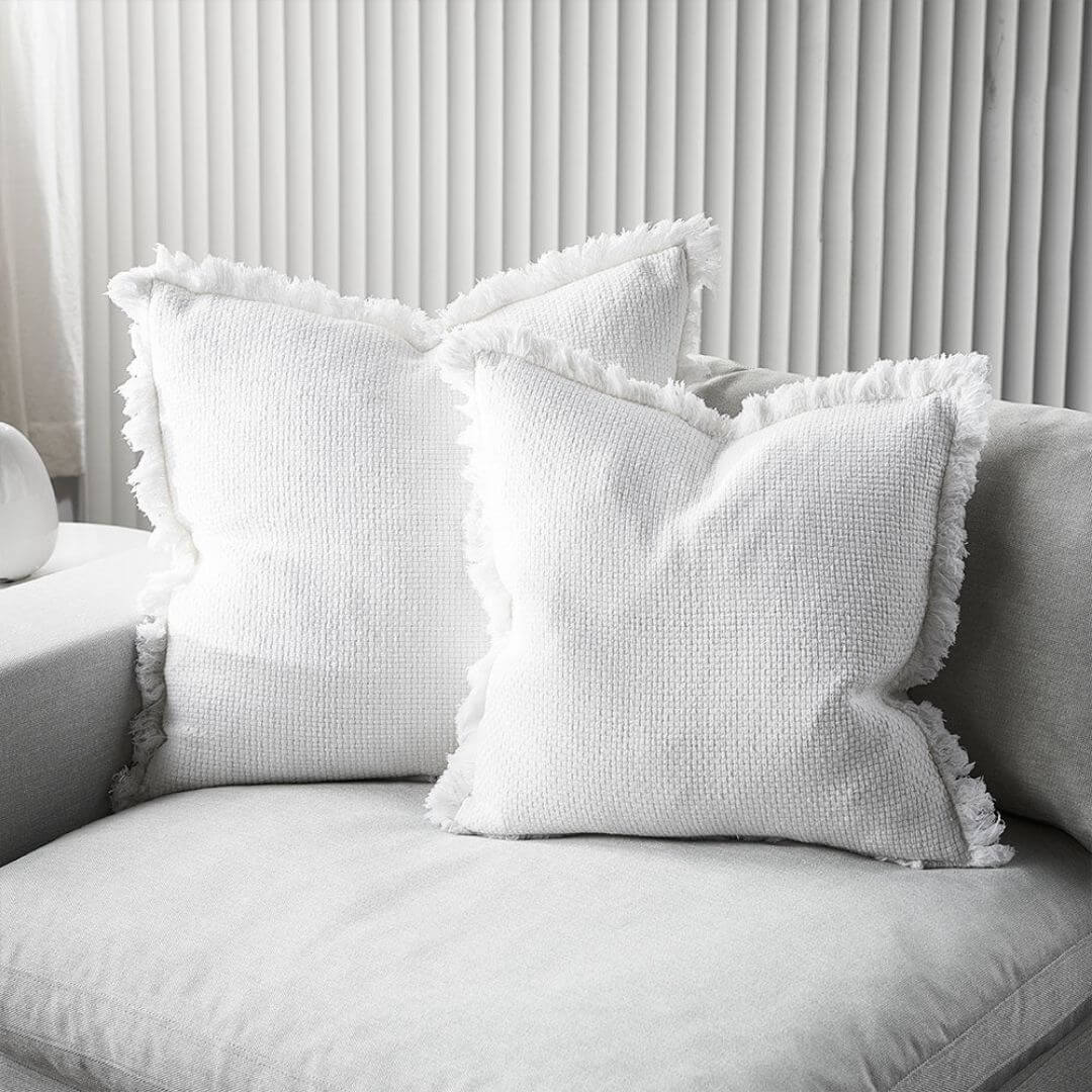 The beautiful off white Square 50cm Chelsea Fringe Cotton Cushion next to a matching 60cm cushion.