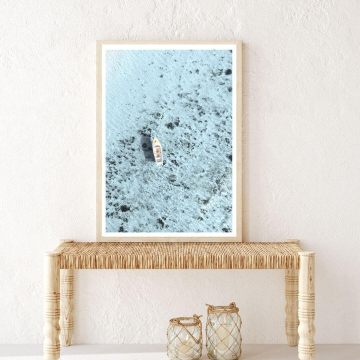 Coastal wall art print of a white boat on blue ocean with timber frame, styled in a hallway – Beautiful Home Decor.