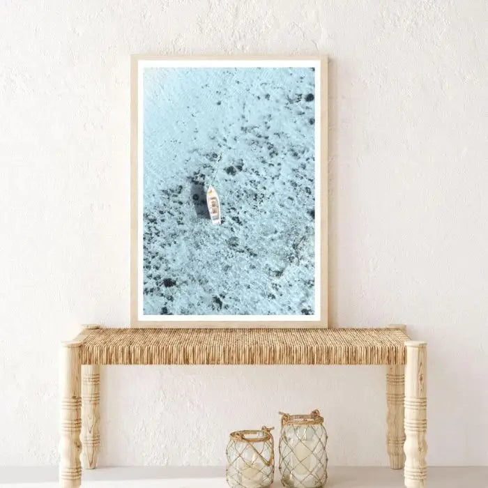 Coastal wall art print of a white boat on blue ocean in timber frame, styled in a hallway at Beautiful Home Decor.