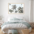 A wall art photo print of coastal palm trees and blue sky with a timber frame to decorate your bedroom empty walls