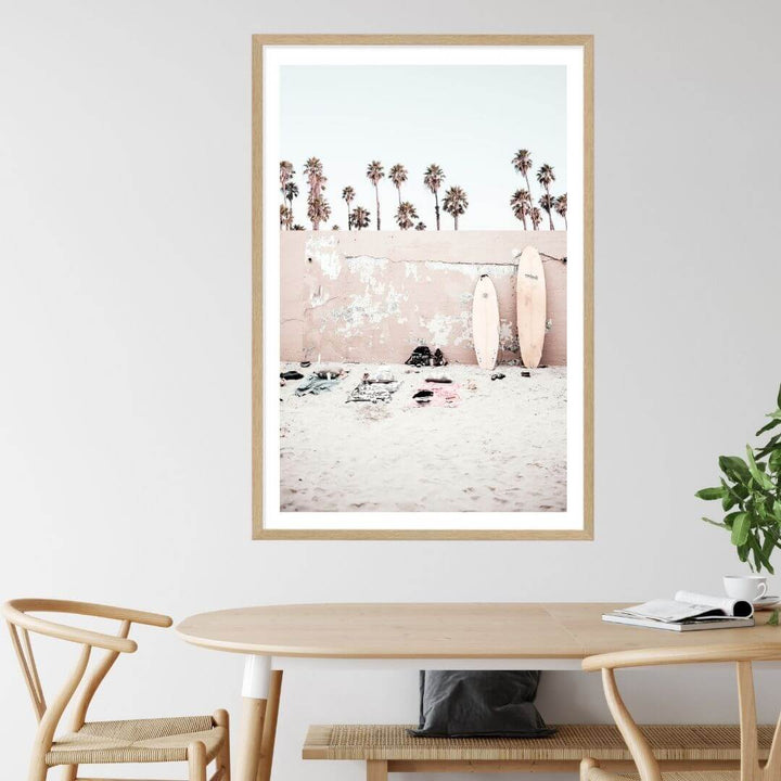 This wall art print of surf boards on the beach with palm trees and a wall is available with a natural timber, black or white frame.