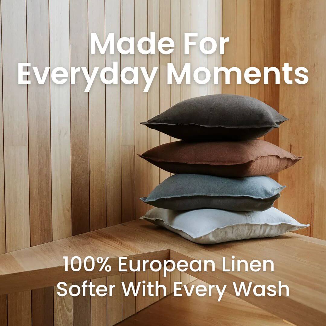 4 50cm and 60cm Como square linen cushions in brown, red, blue and grey on a timber bench.