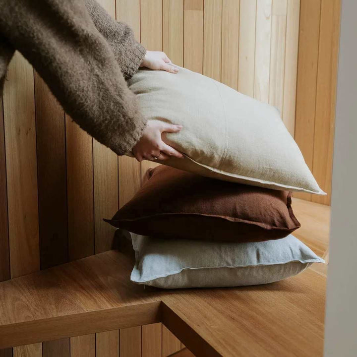 Como 50cm, 60cm Square linen cushion in Sandtone beige, Henna Brown, Haze Light Grey on a bench