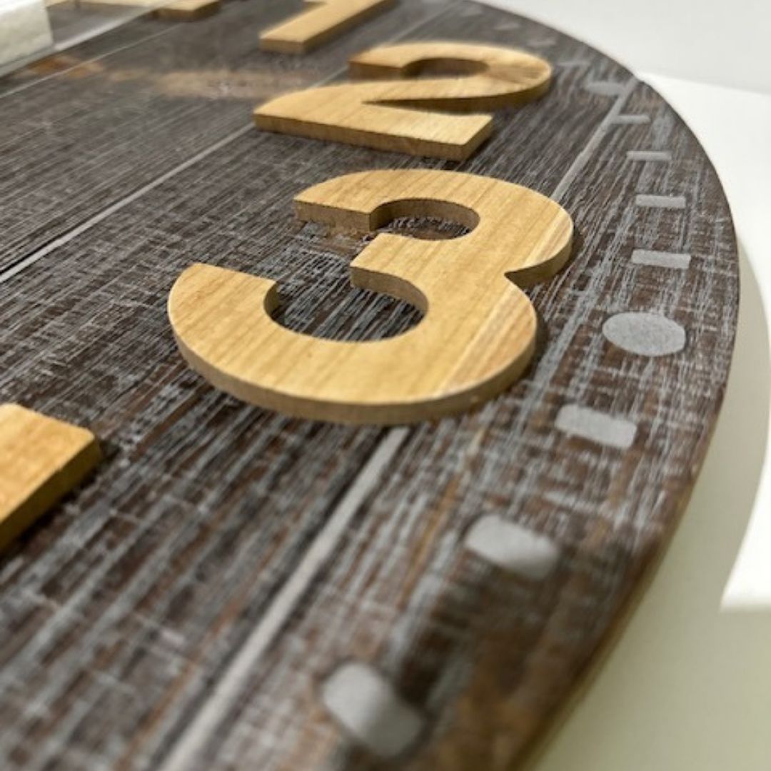 The edge and close-up view of the large 60cm Emporium Slatted Aged Wall Clock with natural timber numbers and grey brown clock face.