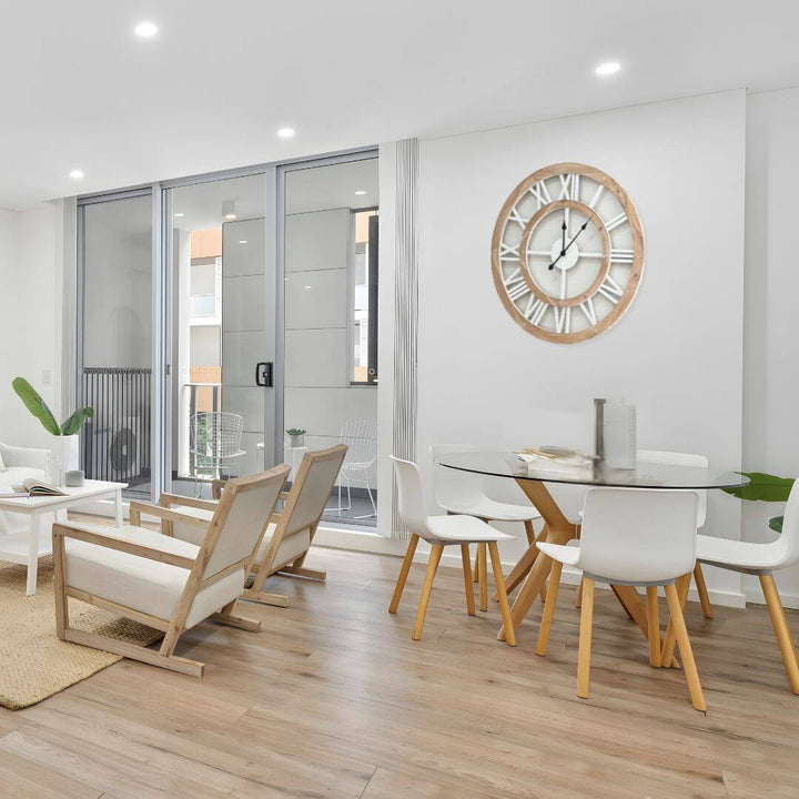 Modern dining room with wooden chairs, glass table, and large coastal hamptons wall clock.