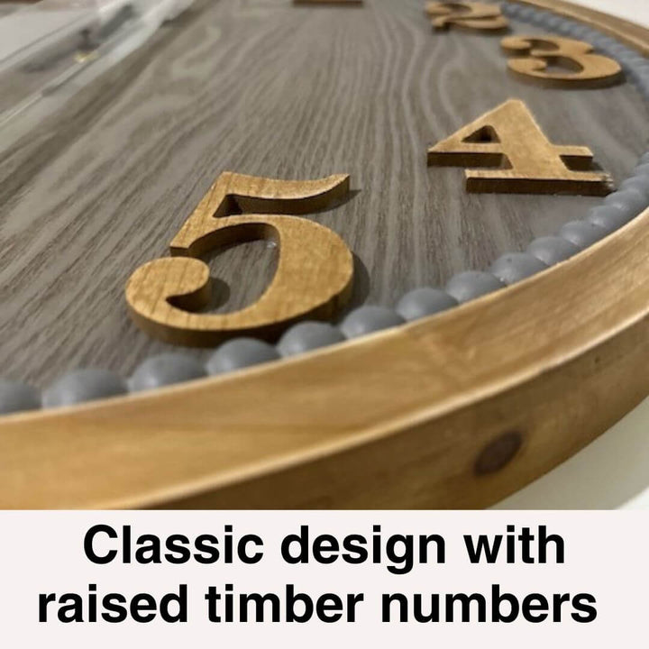 60cm Contemporary Grey Timber Wall Clock with raised timber numbers on a wooden surface