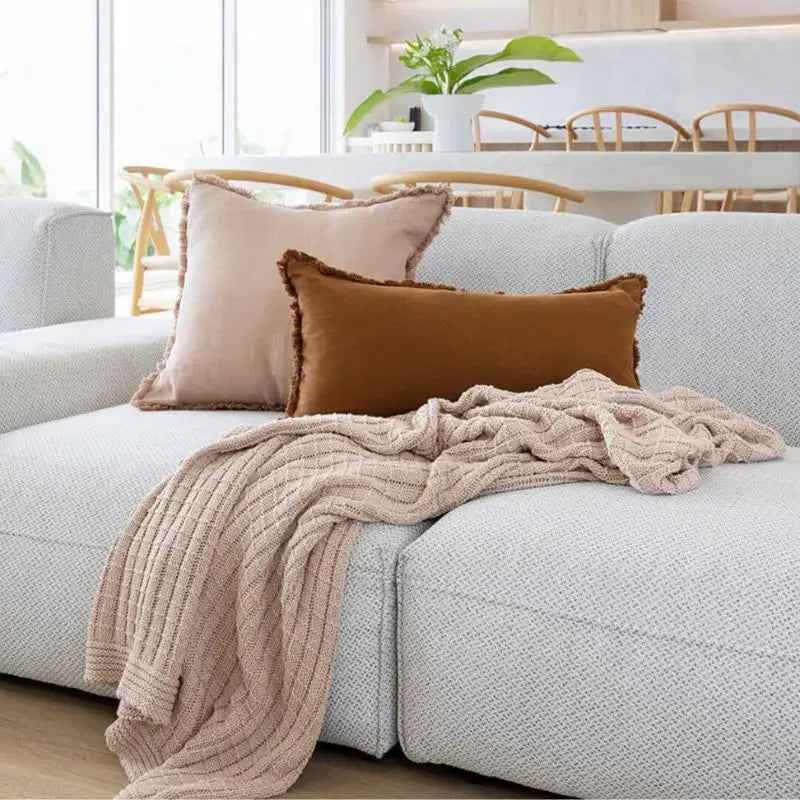 Soft blush cotton throw draped over a sofa and matching linen cushions in Australia