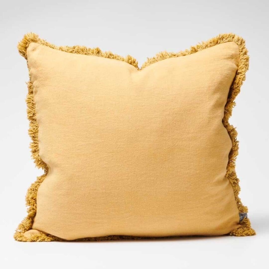 A turmeric Yellow Square 50cm Luca Boho Fringe Cushion with cotton fringe edge.