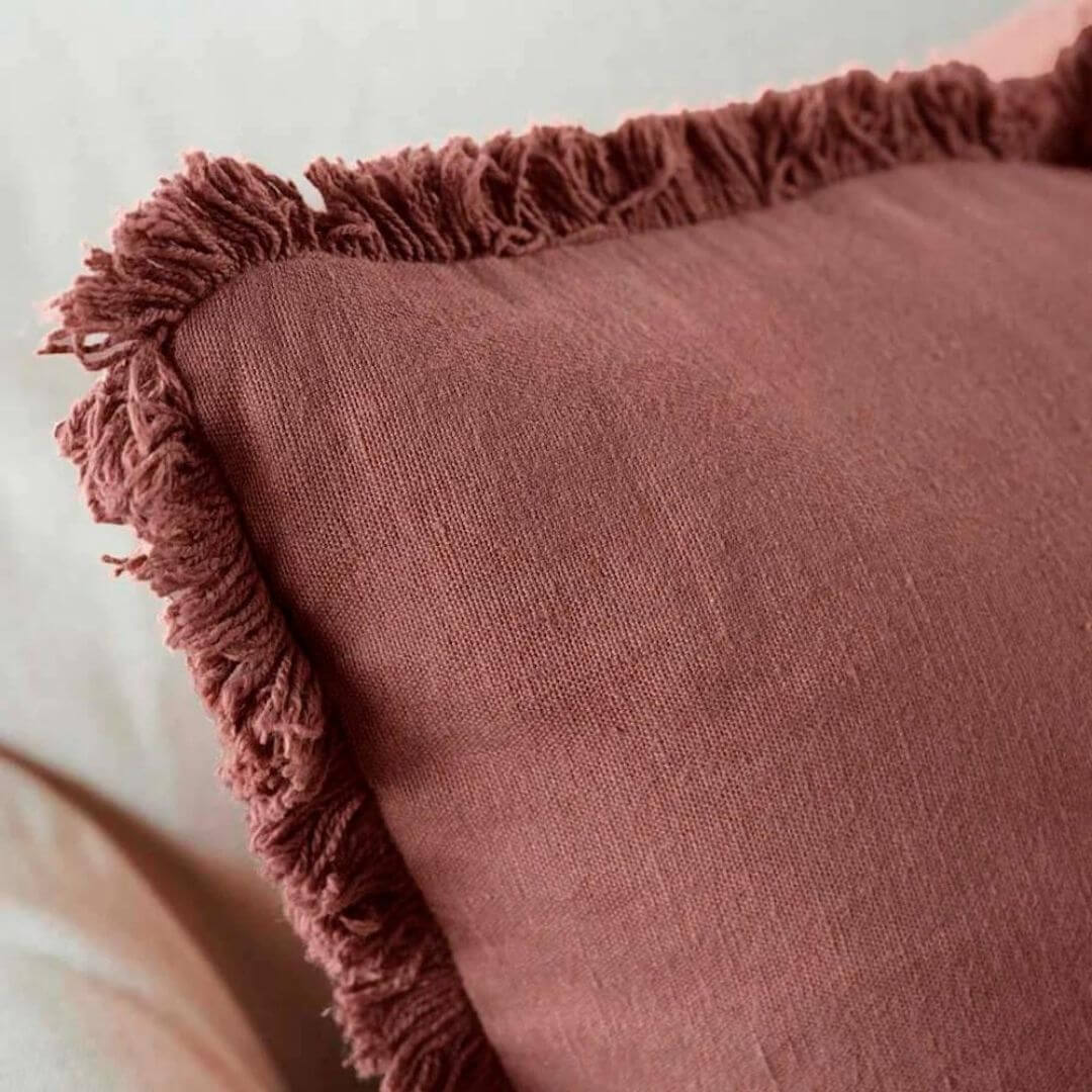A close up view of the cotton fringe on the Square 50cm Luca Boho Cushion in desert rose red.