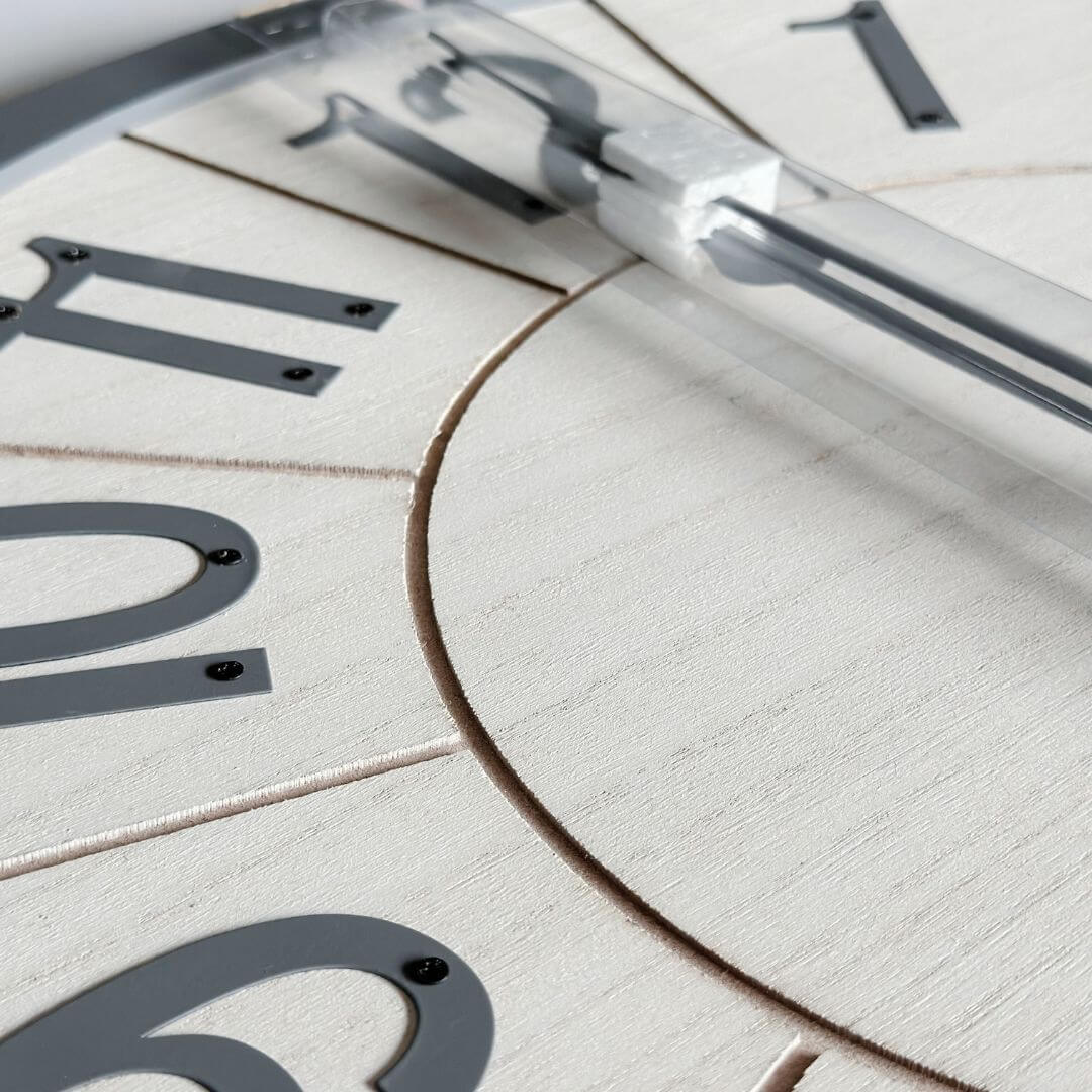 A white clock face of a 60cm Scandi Wall Clock with grey metal numbers.