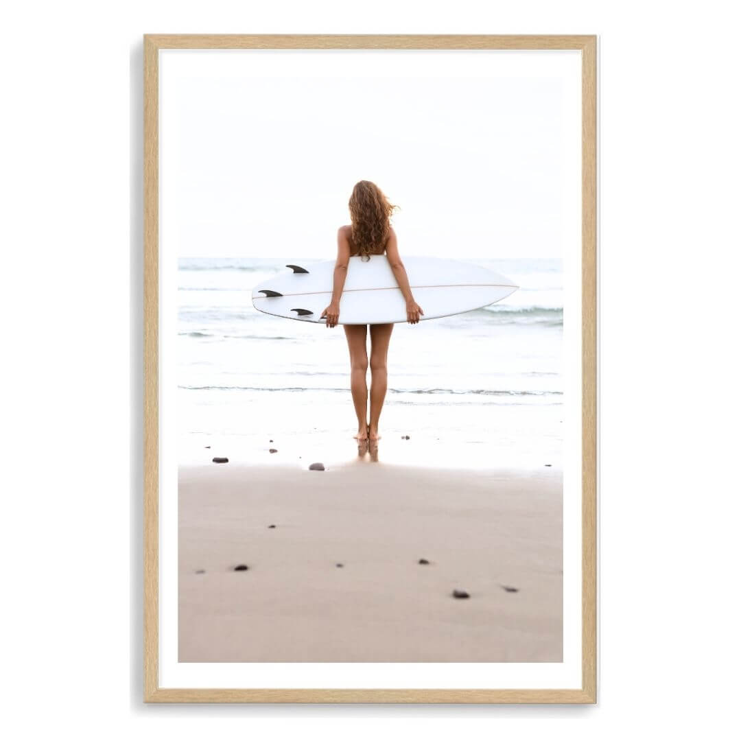 A wall art photo print of the girl with the surfboard with a timber frame, white border by Beautiful Home Decor