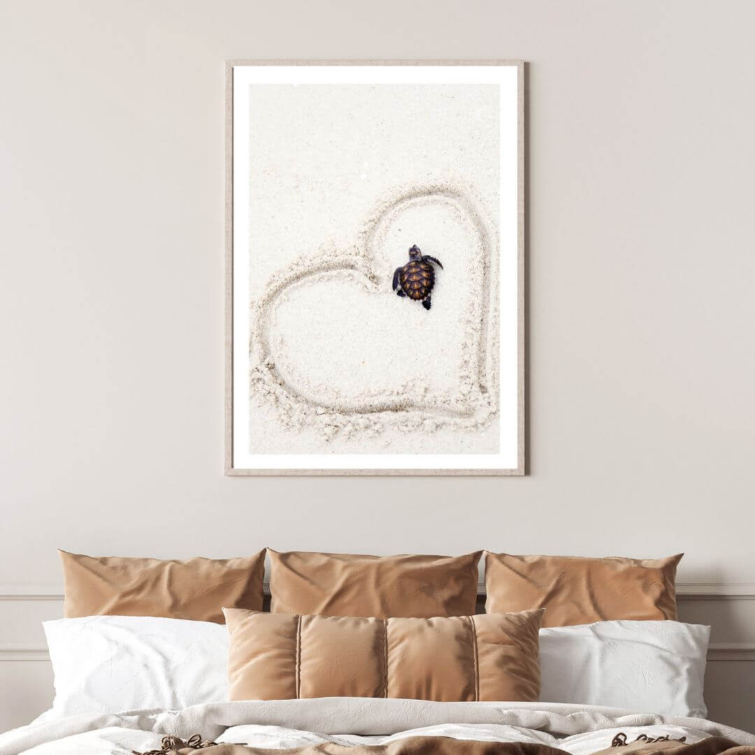 This beach side wall art featuring a cute baby turtle on the sand with a heart drawn around it is available in print with a white frame or without a frame.  