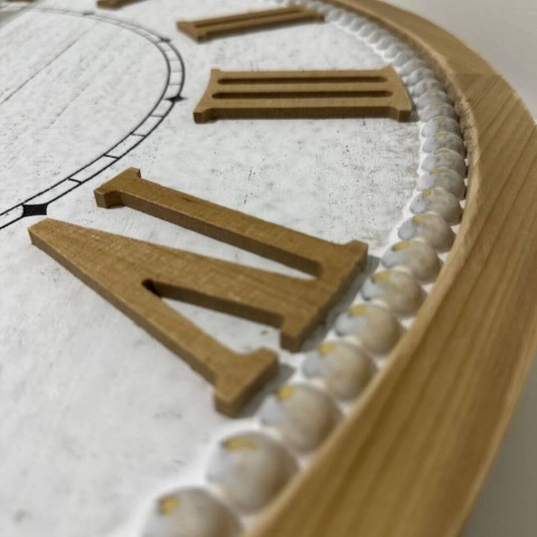A close-up view of the timber numbers on a large 68cm white hamptons roman numerical wall clock.