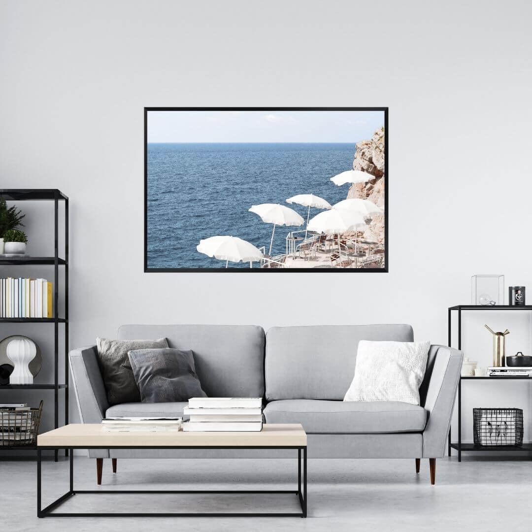 A wall art photo print of white umbrellas on an Amalffi Coast Beach Italy with a black frame on a wall above a sofa by Beautiful HomeDecor
