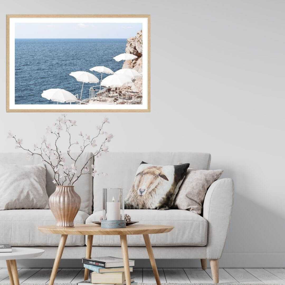 A wall art photo print of white umbrellas on an Amalffi Coast Beach Italy with a timber frame or unframed for your coastal living room behind sofa