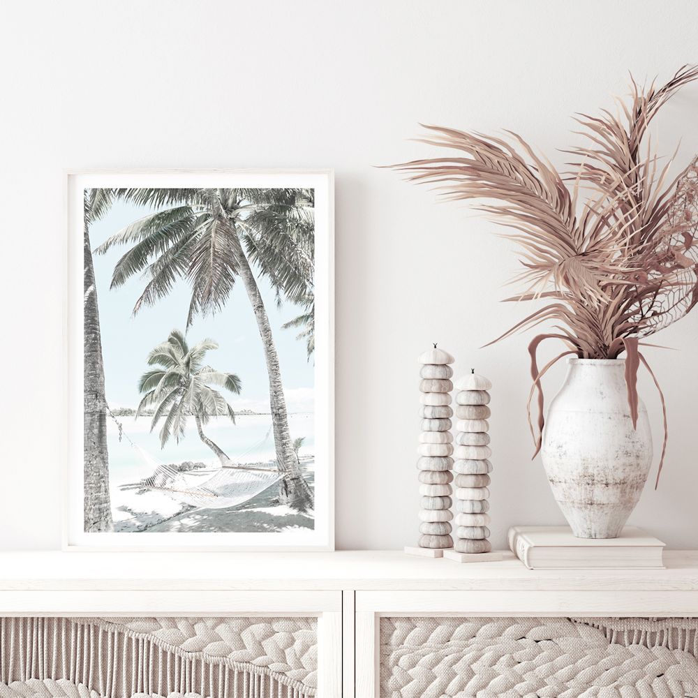 Enjoy a calm and relaxing view with this coastal wall art print featuring a hammock between two palm trees on a tropical beach. 