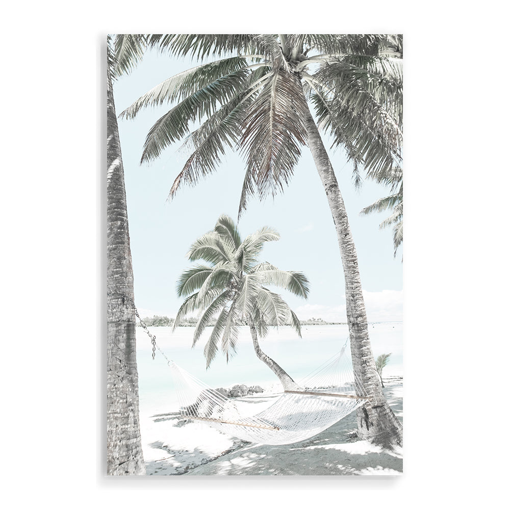 A stretched canvas artwork of a hammock between two palm trees on a tropical beach, available framed or unframed.