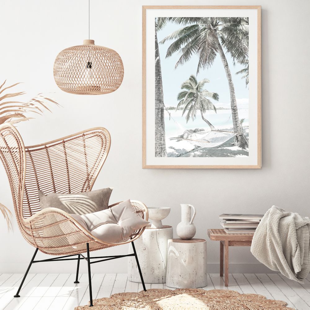 An artwork of a hammock between two palm trees on a tropical beach. This wall art print is available framed or unframed.