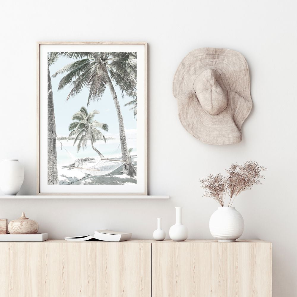 A photo wall art print of a hammock between two palm trees on a tropical beach, available in print and canvas.