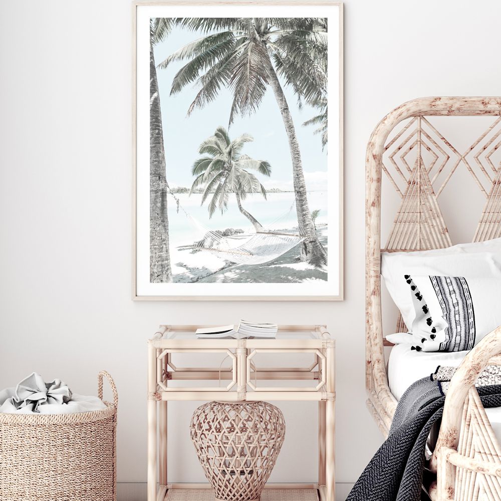 A photo wall art print of a hammock between two palm trees on a tropical beach, available in a framed or unframed print and canvas.