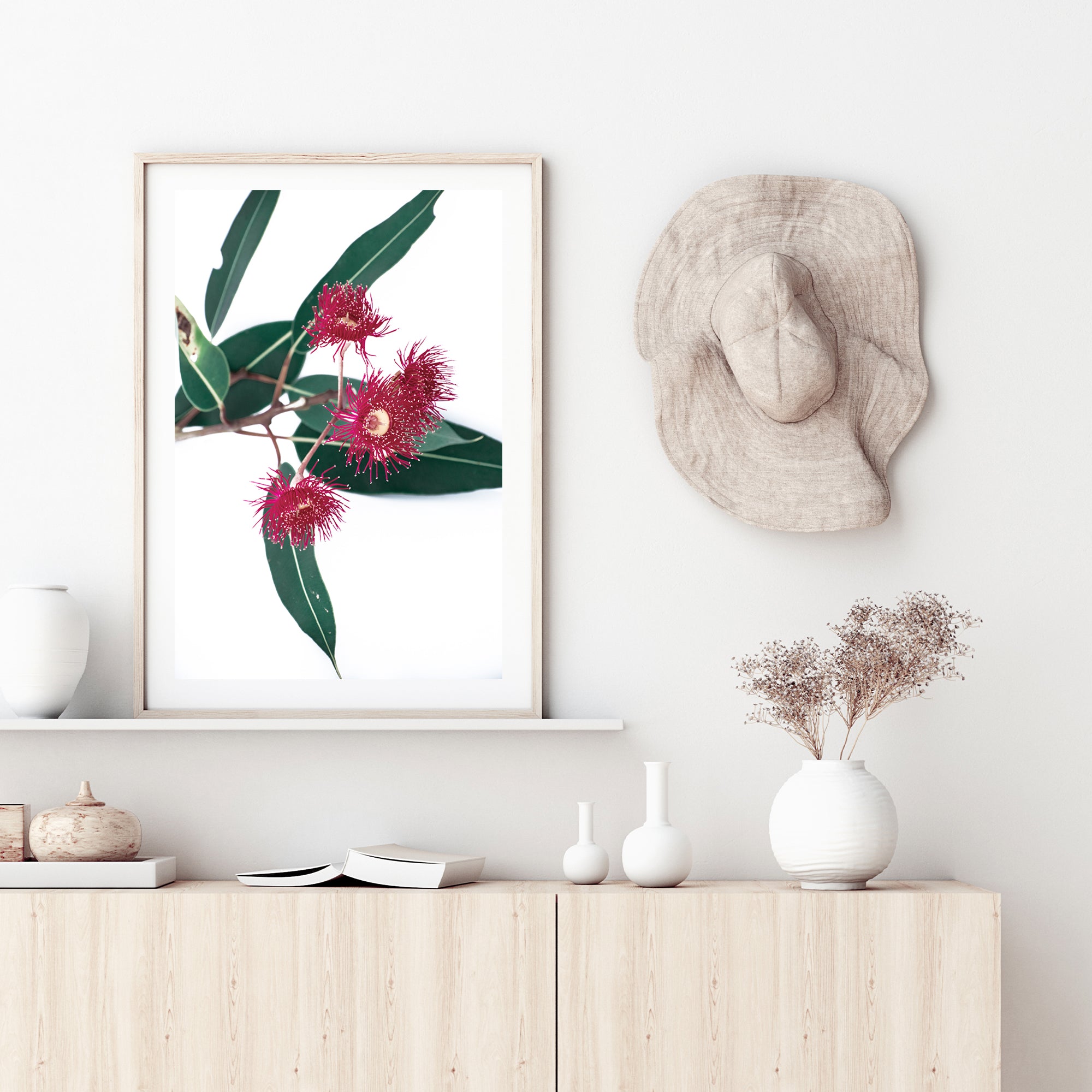 A photo floral wall art featuring green eucalyptus leaves and beautiful red wild flowers, available framed or unframed.