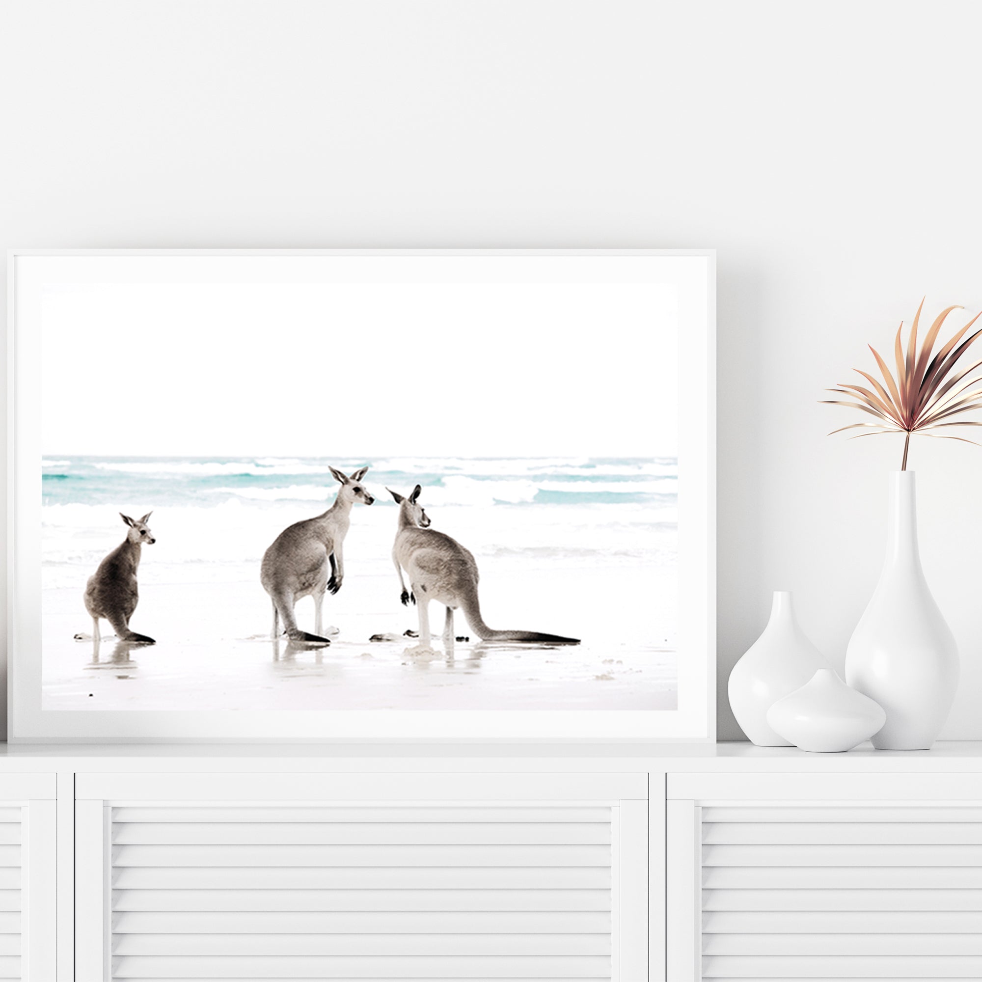 A Hamptons wall art print of three kangaroos enjoying some time on the beach, available in natural timber, black or white frames.