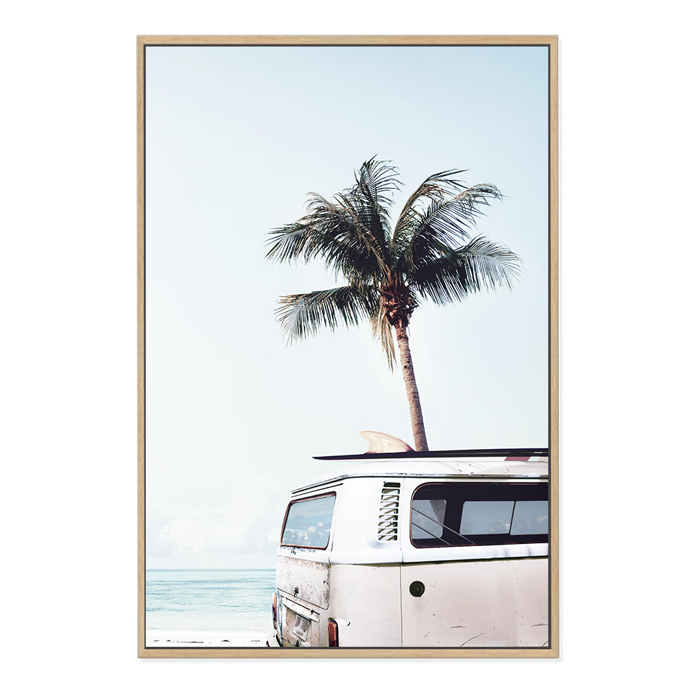 A stretched canvas print of a blue Kombi van at the beach with a blue sky and palm trees, available framed or unframed.