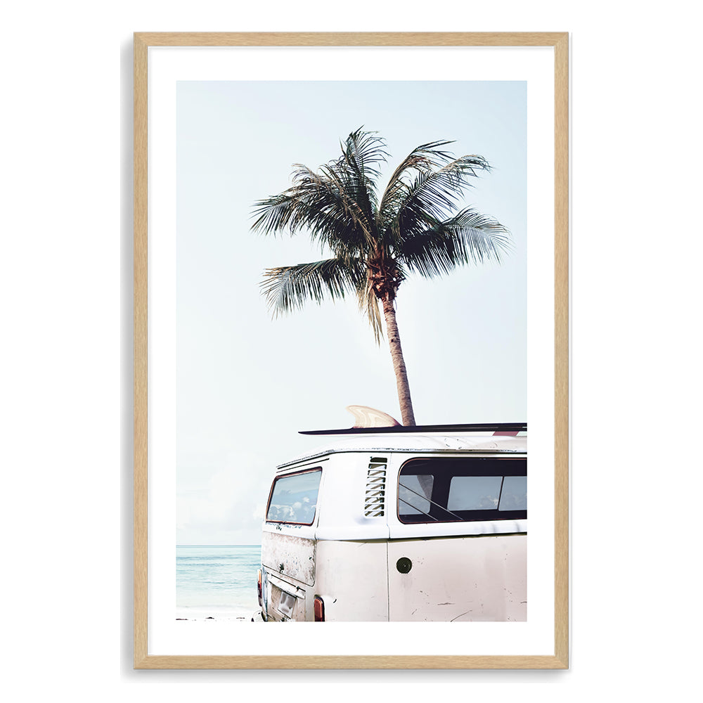 A wall art print of a blue Kombi van at the beach with a blue sky and palm trees, available in canvas or photo print.