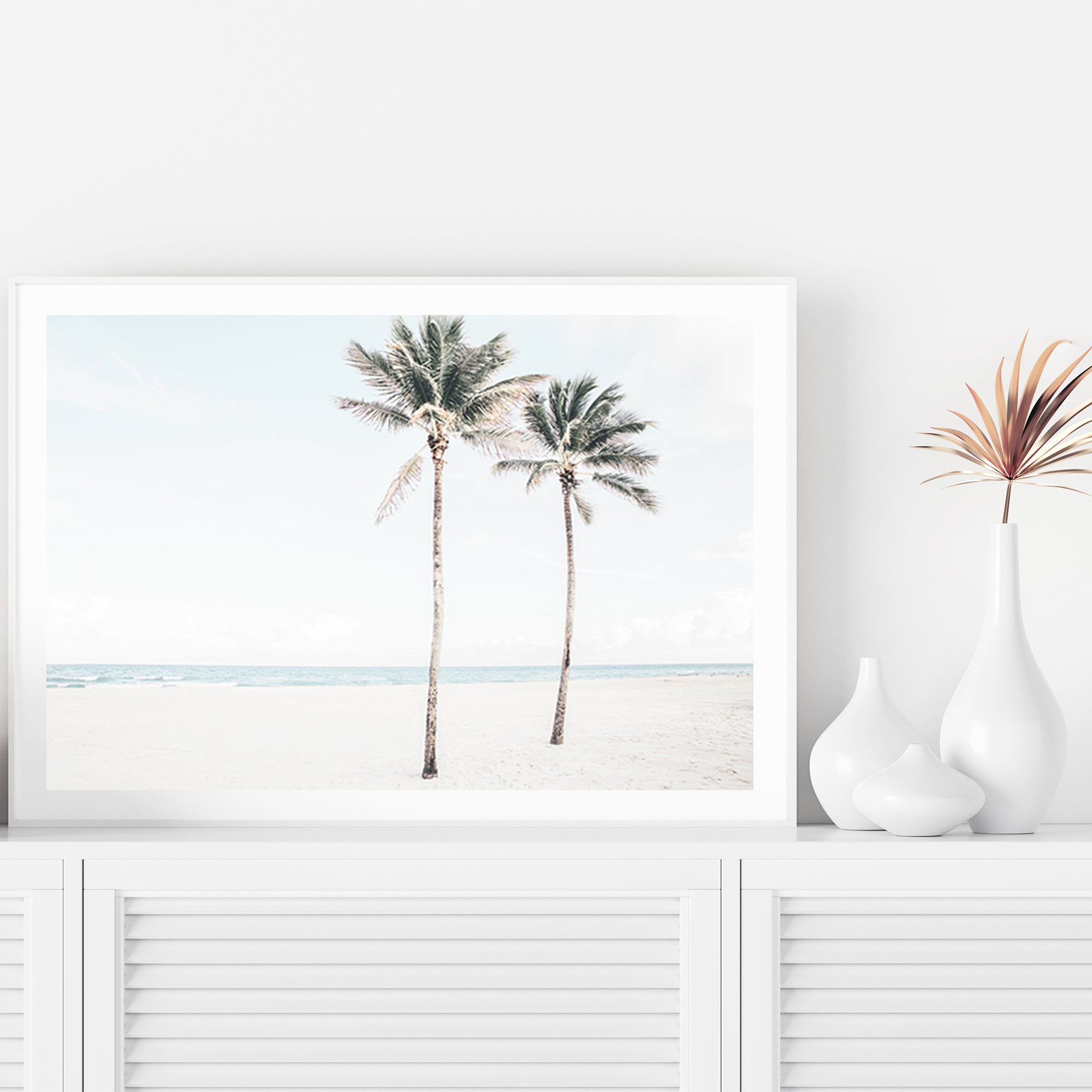 A stretched canvas Hamptons artwork of two palm trees and the beach, available unframed or timber, black or white frames.